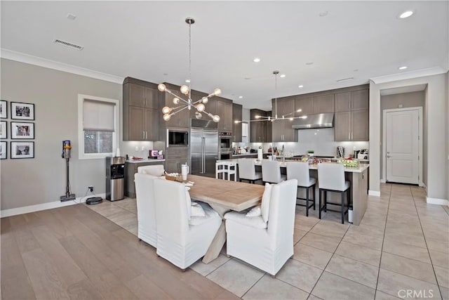 dining space featuring light tile patterned floors, crown molding, and an inviting chandelier