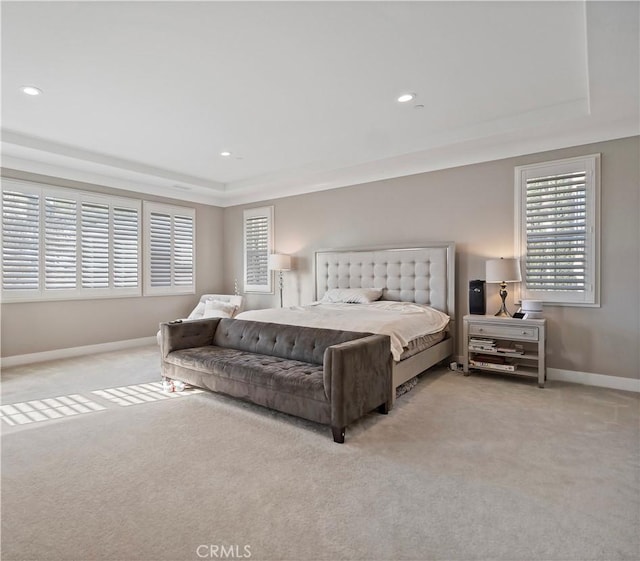 bedroom featuring light colored carpet and a tray ceiling