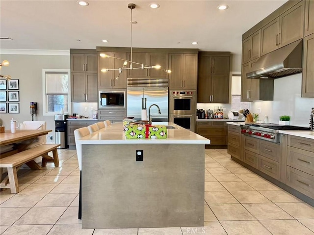 kitchen with crown molding, pendant lighting, extractor fan, a kitchen island with sink, and built in appliances