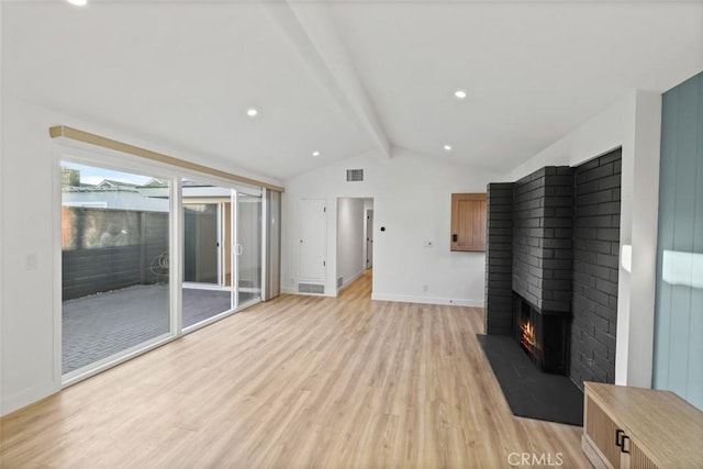 unfurnished living room with a fireplace, lofted ceiling with beams, and light hardwood / wood-style floors