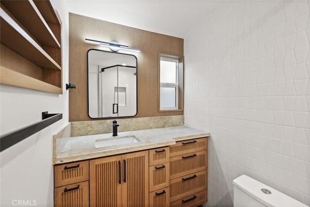 bathroom featuring vanity, tile walls, and toilet