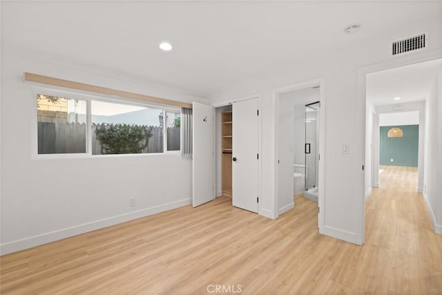 unfurnished bedroom featuring a closet, connected bathroom, and light hardwood / wood-style flooring