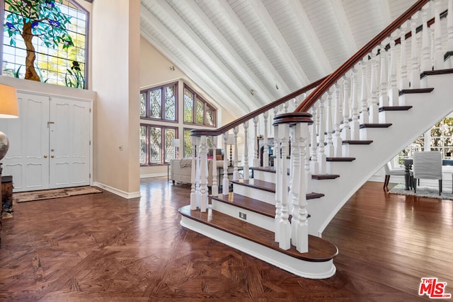 entryway with beam ceiling, high vaulted ceiling, and dark parquet flooring