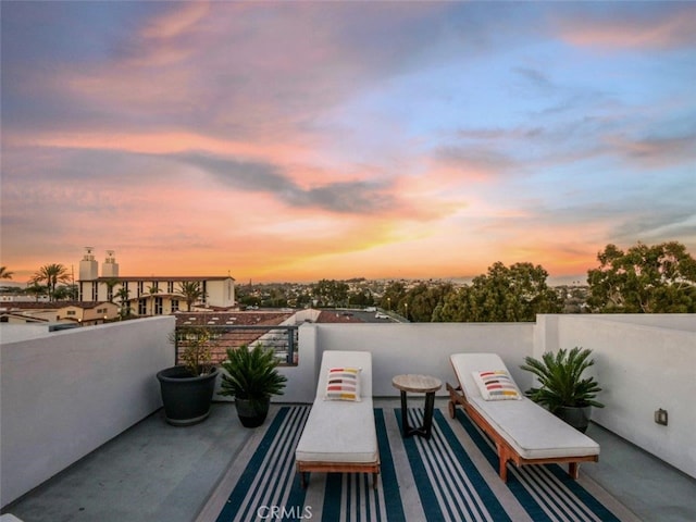 patio terrace at dusk featuring a balcony