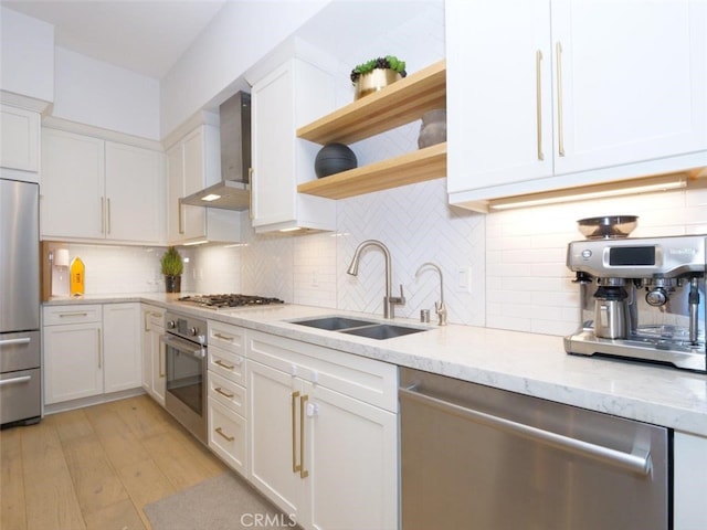 kitchen featuring white cabinets, appliances with stainless steel finishes, sink, and wall chimney range hood