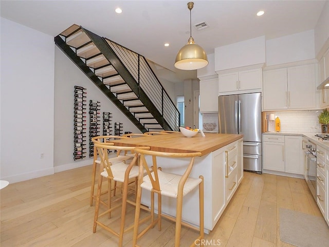 kitchen featuring white cabinetry, decorative light fixtures, light hardwood / wood-style flooring, and appliances with stainless steel finishes