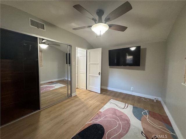 bedroom featuring lofted ceiling, light hardwood / wood-style flooring, a closet, and ceiling fan