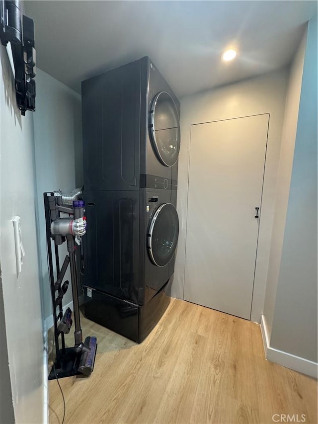 laundry area featuring stacked washer / dryer and light hardwood / wood-style floors