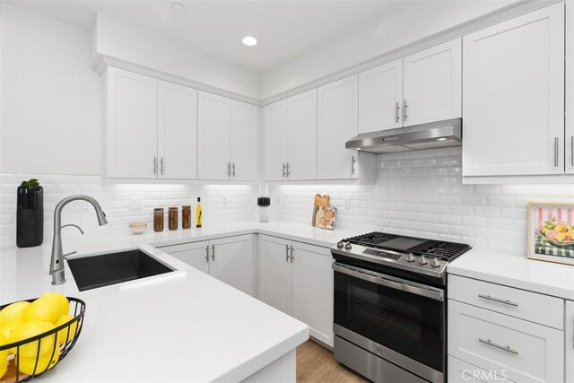 kitchen with white cabinets, decorative backsplash, sink, stainless steel range with gas cooktop, and light hardwood / wood-style flooring