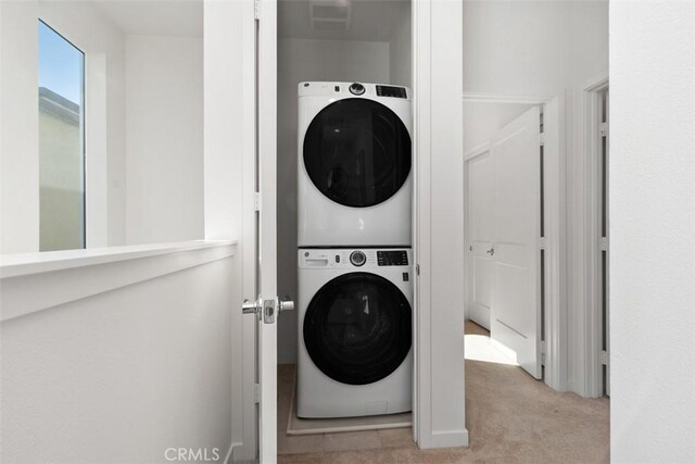 laundry room featuring stacked washing maching and dryer and light carpet