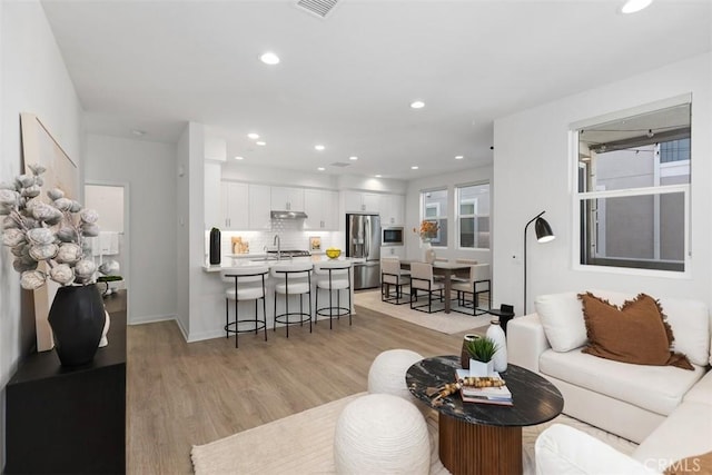 living area with light wood-style flooring, recessed lighting, and visible vents