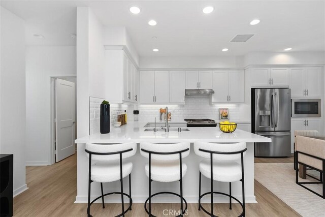 kitchen featuring stainless steel fridge with ice dispenser, light hardwood / wood-style floors, built in microwave, white cabinets, and sink