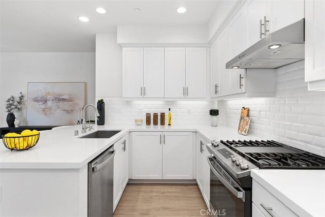 kitchen with stainless steel appliances, decorative backsplash, white cabinets, and sink