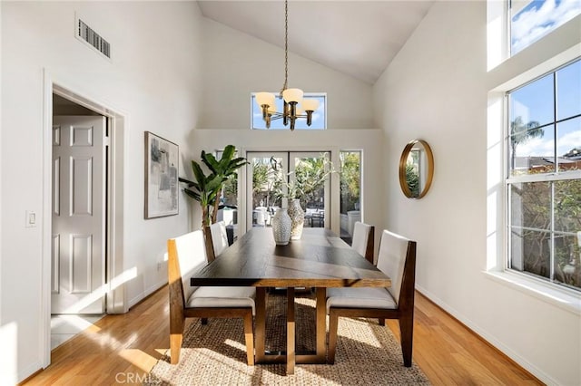 dining area featuring light hardwood / wood-style floors, high vaulted ceiling, and a notable chandelier