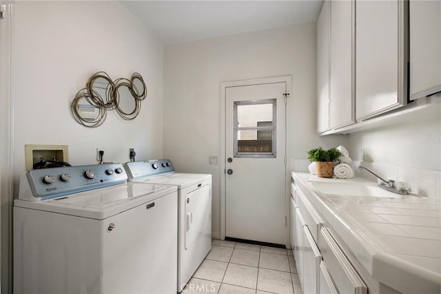 clothes washing area with cabinets, light tile patterned flooring, independent washer and dryer, and sink