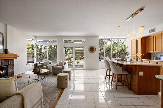 living room featuring a brick fireplace, light tile patterned flooring, and sink