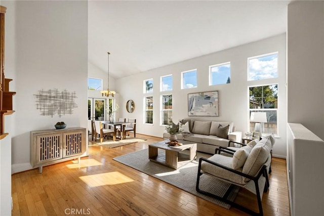 living room featuring a towering ceiling, an inviting chandelier, and light hardwood / wood-style flooring