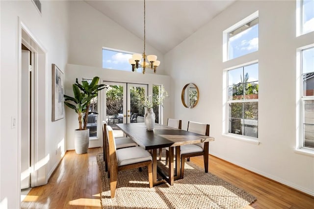 dining space featuring high vaulted ceiling, plenty of natural light, an inviting chandelier, and light hardwood / wood-style flooring