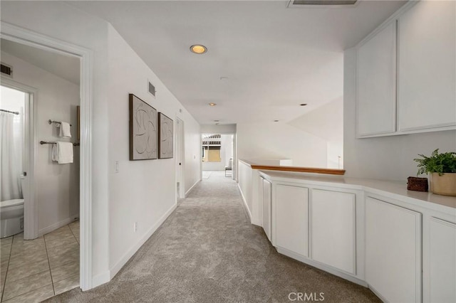 hallway featuring light carpet and vaulted ceiling