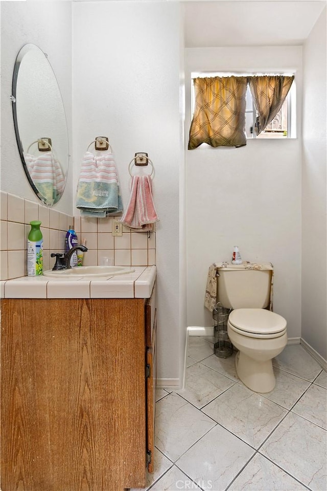 bathroom featuring toilet, tile patterned flooring, decorative backsplash, and vanity