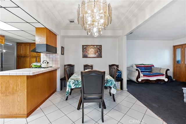 dining room with crown molding, light tile patterned floors, and an inviting chandelier