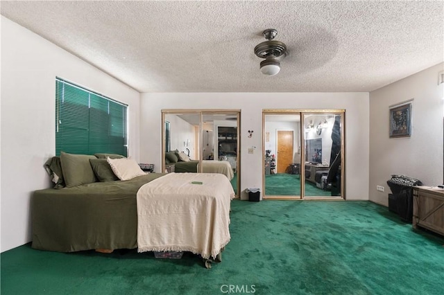 carpeted bedroom with ceiling fan, multiple closets, and a textured ceiling