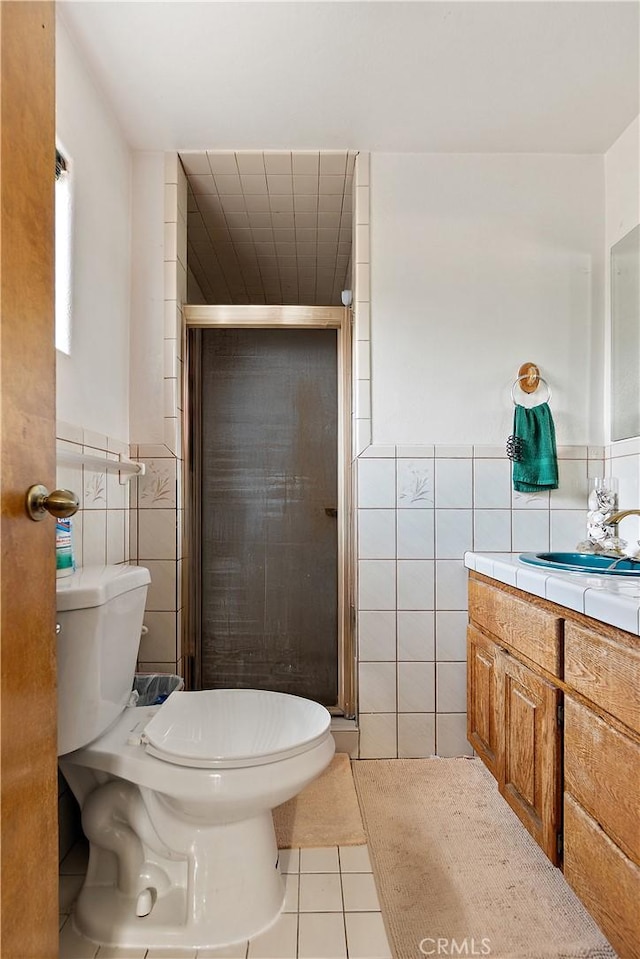 bathroom with toilet, tile patterned flooring, tile walls, an enclosed shower, and vanity