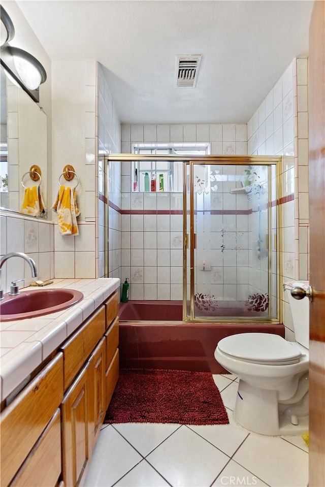 bathroom with toilet, vanity, tile walls, tile patterned flooring, and backsplash