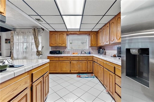 kitchen with tile counters, backsplash, and stainless steel fridge