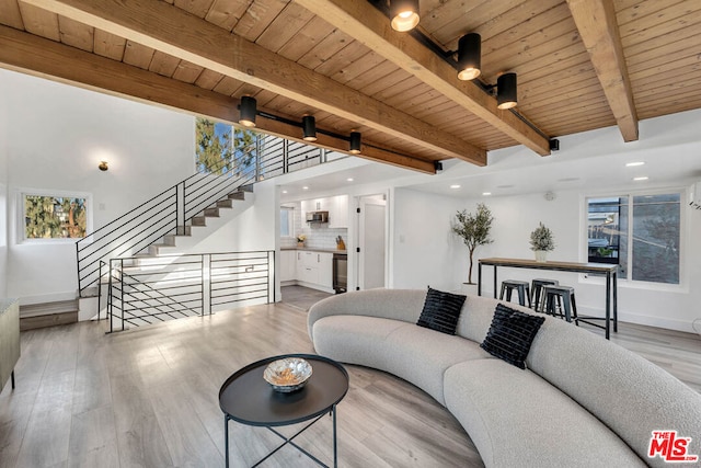 living room featuring ceiling fan, light hardwood / wood-style flooring, beamed ceiling, and wood ceiling