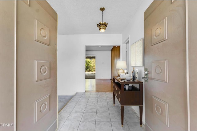 corridor with a textured ceiling and light tile patterned floors