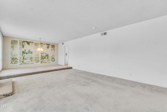 carpeted empty room with an inviting chandelier and a textured ceiling