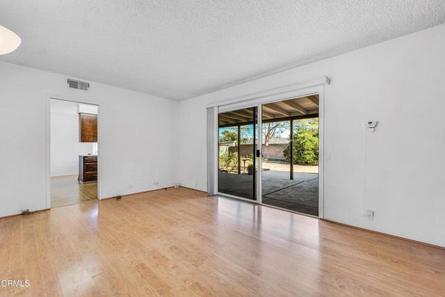 unfurnished room featuring a textured ceiling and light hardwood / wood-style floors