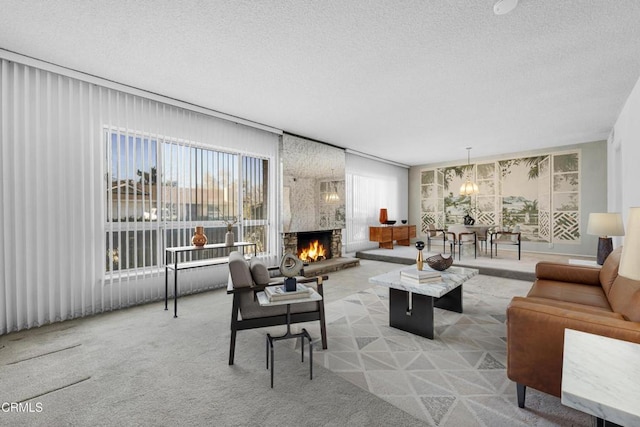 living room with a textured ceiling, a fireplace, light colored carpet, and an inviting chandelier