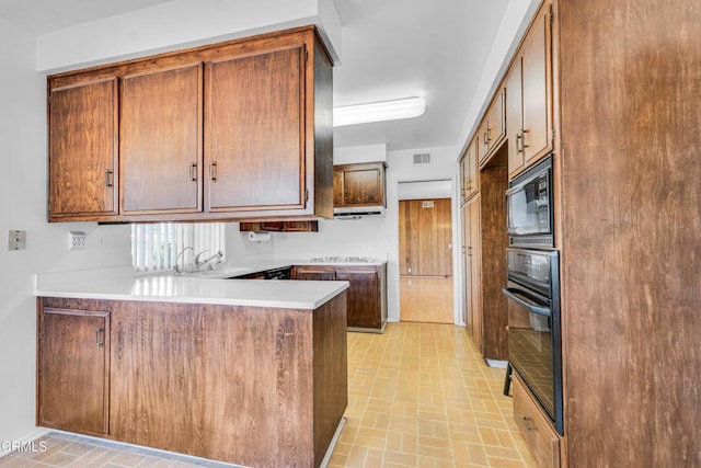 kitchen featuring black appliances, kitchen peninsula, and sink