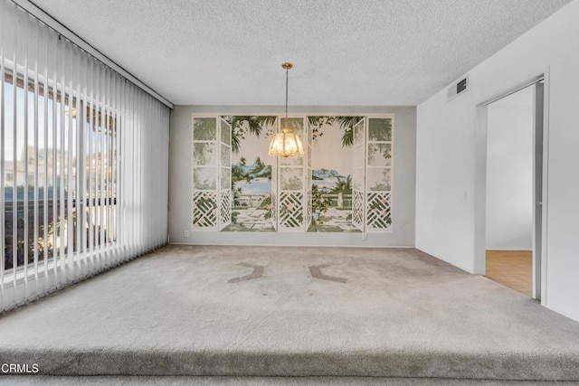 unfurnished dining area with a textured ceiling, carpet floors, and a notable chandelier