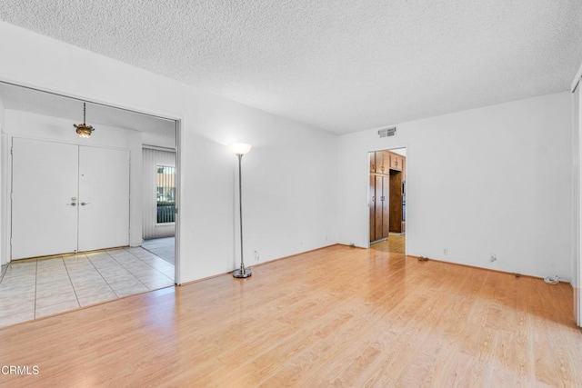 spare room featuring a textured ceiling and light hardwood / wood-style floors