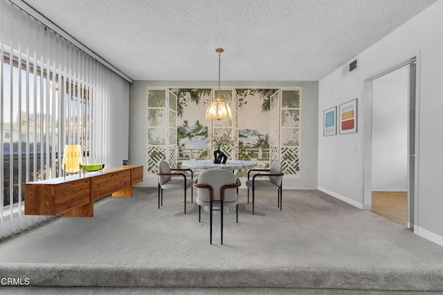 carpeted dining space featuring a notable chandelier and a textured ceiling