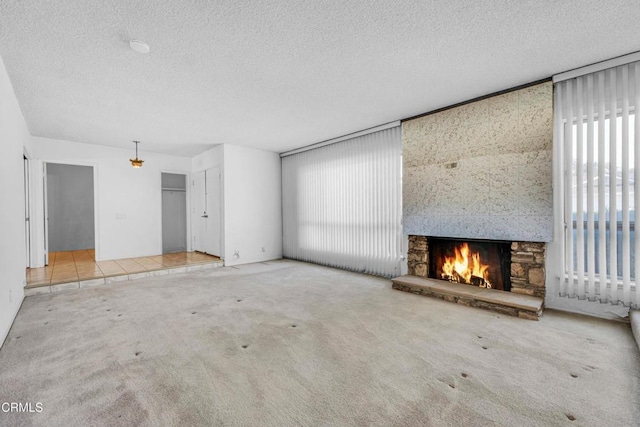 unfurnished living room with a textured ceiling, a fireplace, and light colored carpet