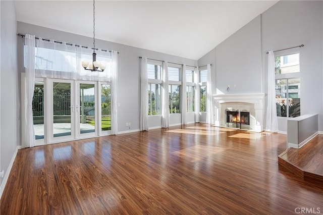 unfurnished living room featuring hardwood / wood-style flooring, a notable chandelier, and high vaulted ceiling