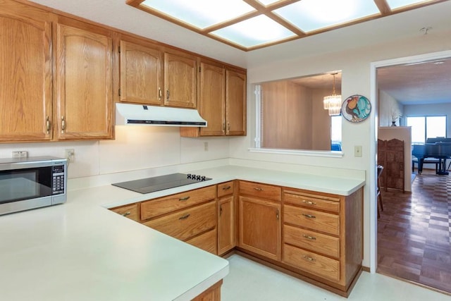 kitchen featuring black electric stovetop, decorative light fixtures, kitchen peninsula, and an inviting chandelier