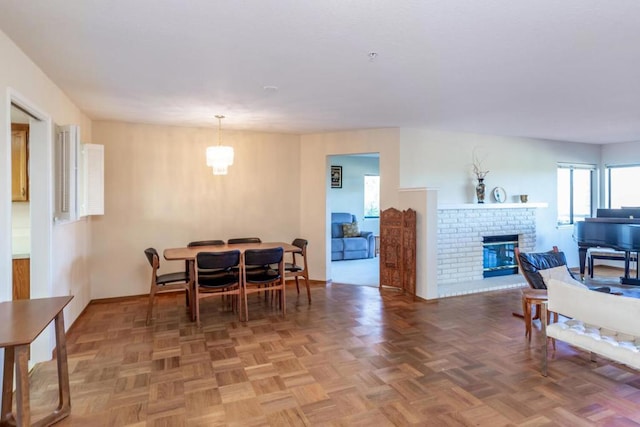 dining room featuring parquet flooring, an inviting chandelier, and a fireplace