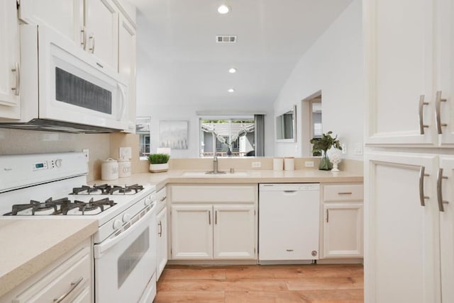 kitchen with white appliances, lofted ceiling, white cabinetry, sink, and light wood-type flooring