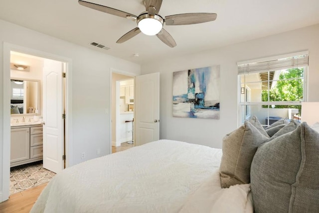 bedroom with ceiling fan, light hardwood / wood-style floors, ensuite bathroom, and sink