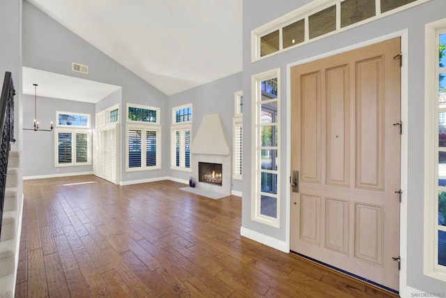 foyer entrance featuring wood-type flooring, a chandelier, and high vaulted ceiling