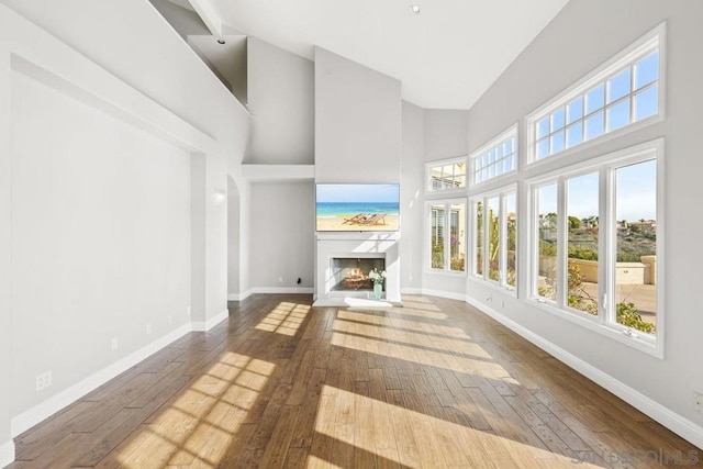 unfurnished living room featuring wood-type flooring and a towering ceiling