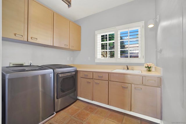 clothes washing area featuring cabinets, sink, light tile patterned floors, and washing machine and clothes dryer