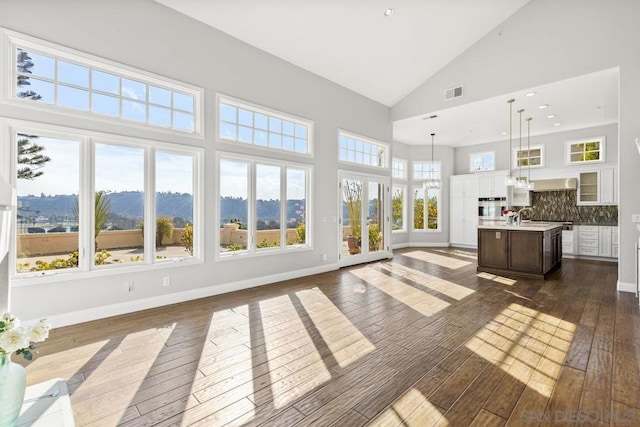 unfurnished sunroom featuring lofted ceiling, a mountain view, plenty of natural light, and sink