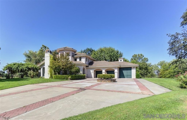 mediterranean / spanish house featuring a garage and a front yard