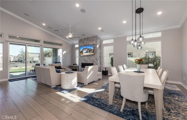 dining area with ceiling fan, light wood-type flooring, a premium fireplace, lofted ceiling, and ornamental molding